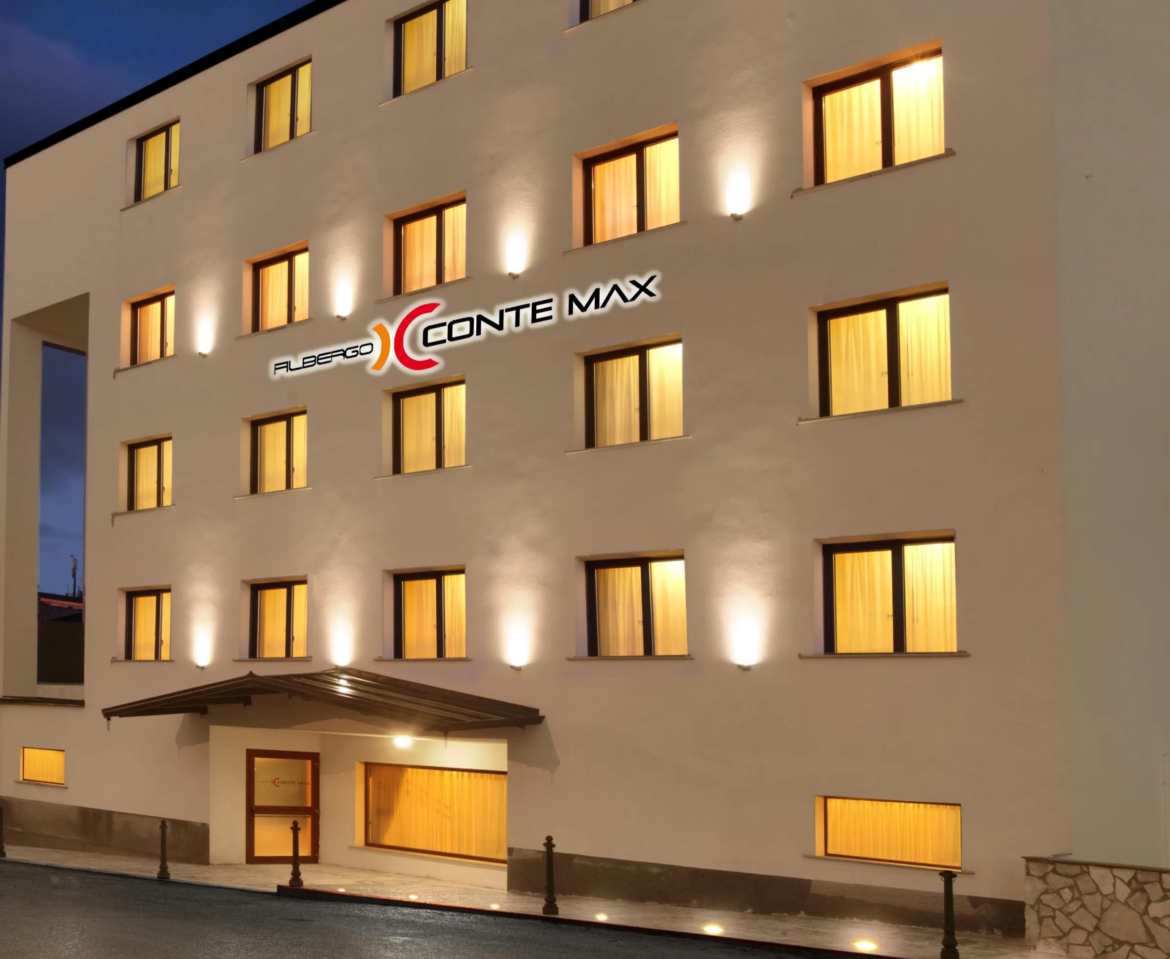 La facciata dell’Albergo Conte Max illuminata la sera